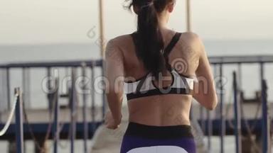年轻女子在海边的码头上<strong>奔跑</strong>。 <strong>晨跑</strong>的运动女孩。 从女运动员的背后看